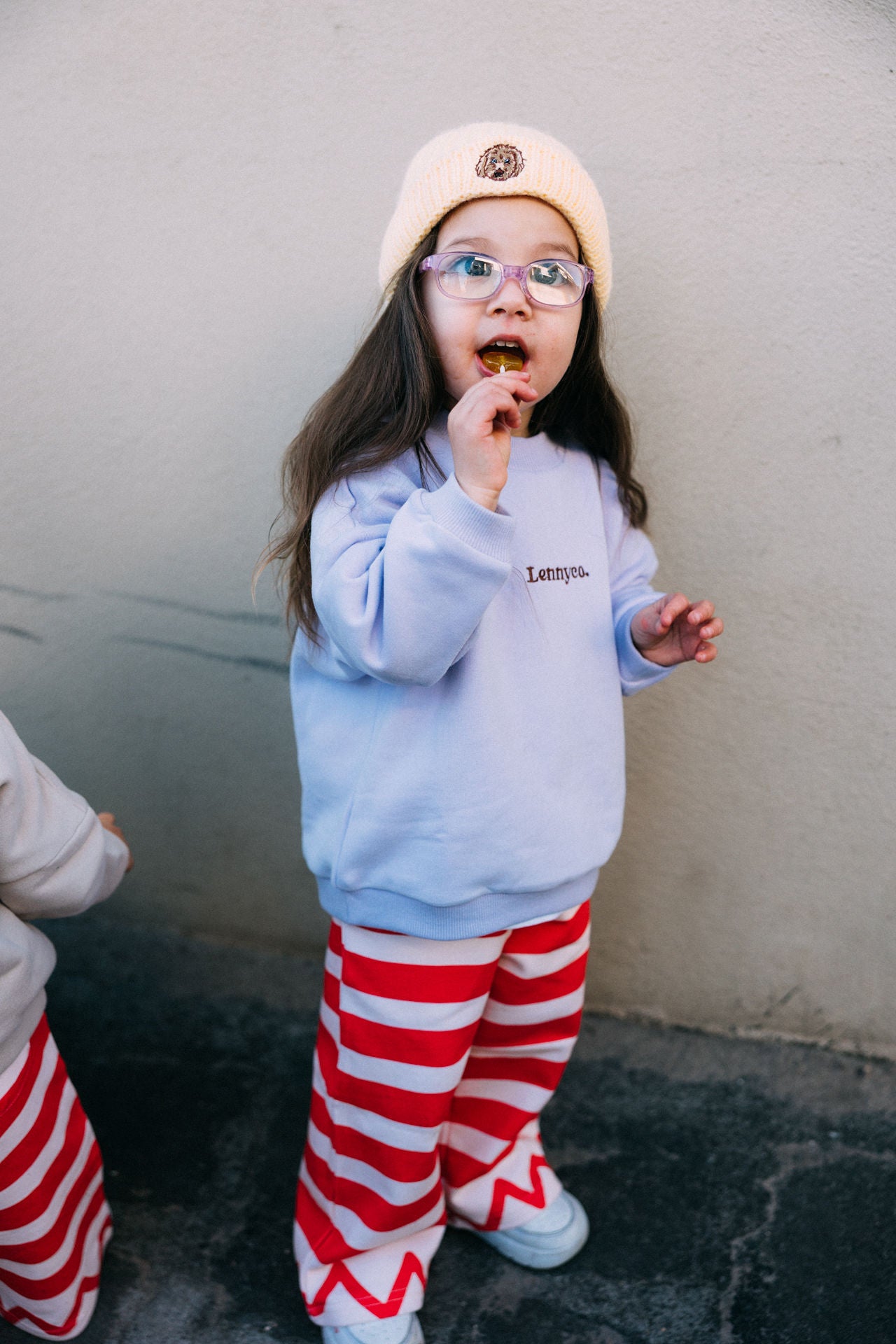 kids winter jumper, lilac jumper for kids, little girl wearing purple jumper and red stripe pants and yellow beanie, kids winter outfit