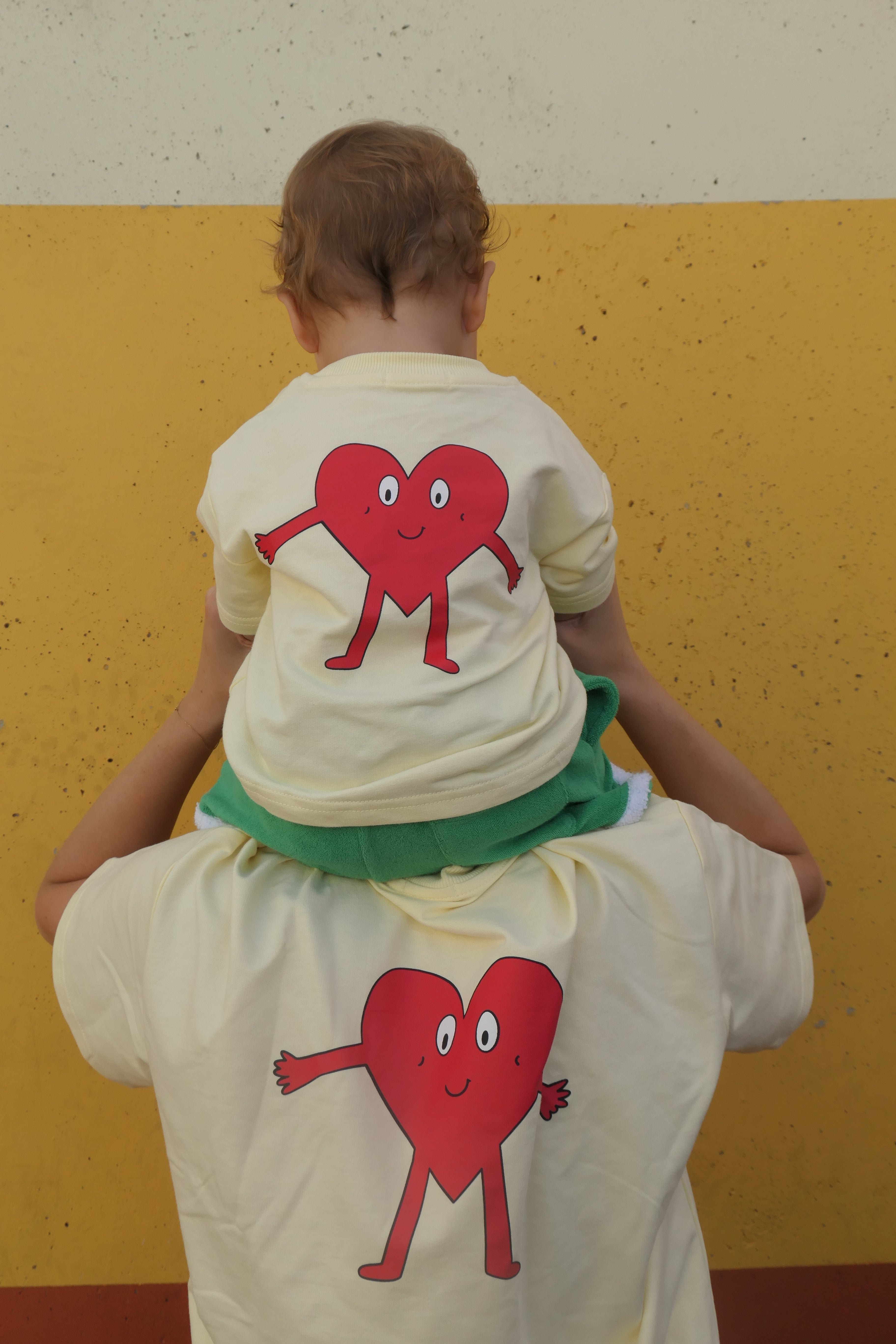 Mum & baby wearing yellow tshirt with giant heart symbol design on back