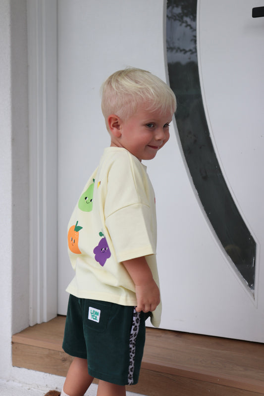 little boy wearing yellow tshirt with fruit graphic prints on it and dark green cord shorts